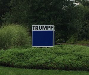 Business sign reading "Trumpf" with bushes and other landscaping around it.  