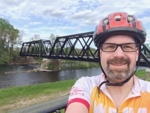 Selfie of Sean with bike bridge and river in background
