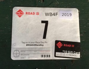 Rectangular ride or race bib with the brand "Road ID", and the number seven on it.  Also labeled as WB4F 2019.