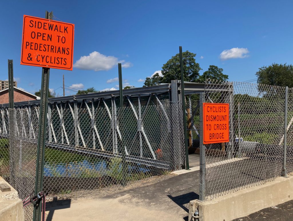 Entrance to temporary walking bridge, signs read "bridge for pedestrians and cyclists only" and "cyclists must dismount before crossing bridge"
