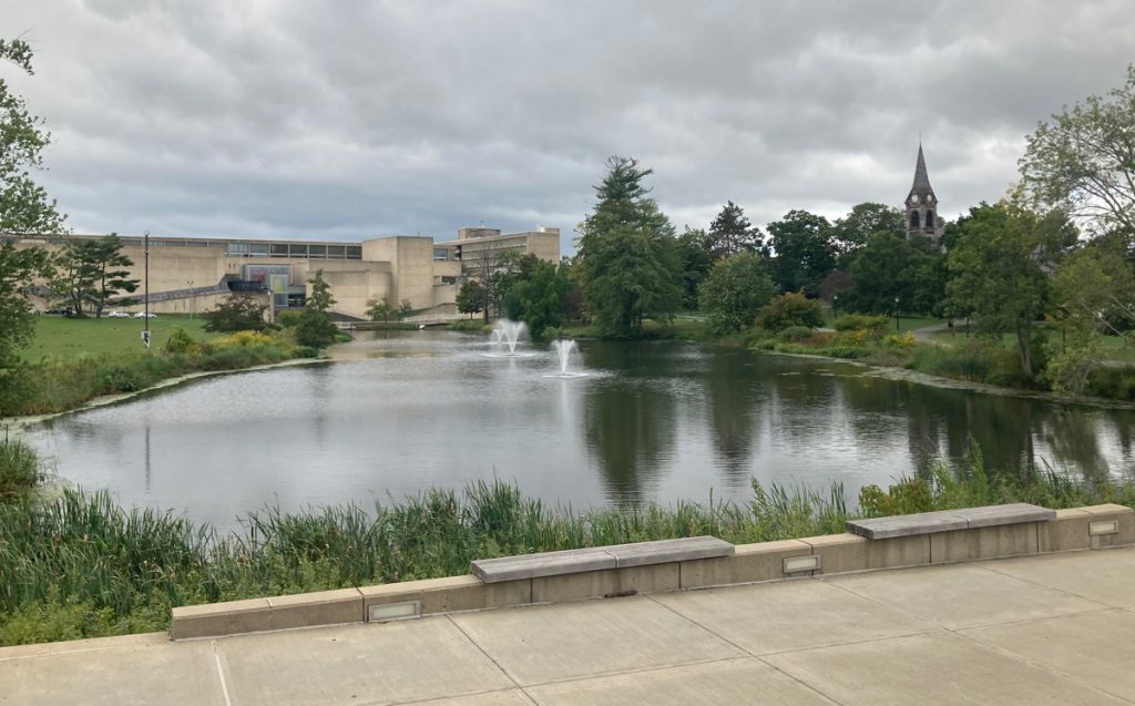Large pond on the campus of the university of massachusetts.  Buildings and trees can be seen around it.